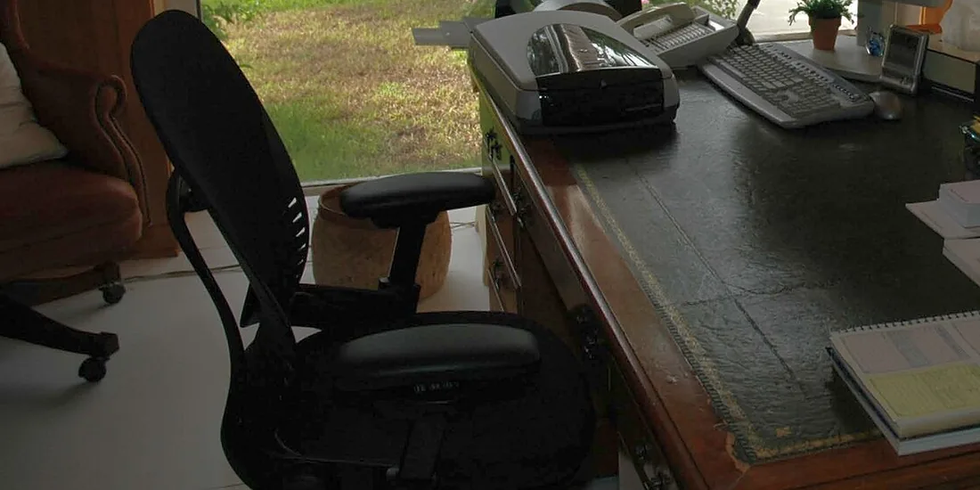 Schwarzer Stuhl an einem Schreibtisch mit Tastatur und Fenster